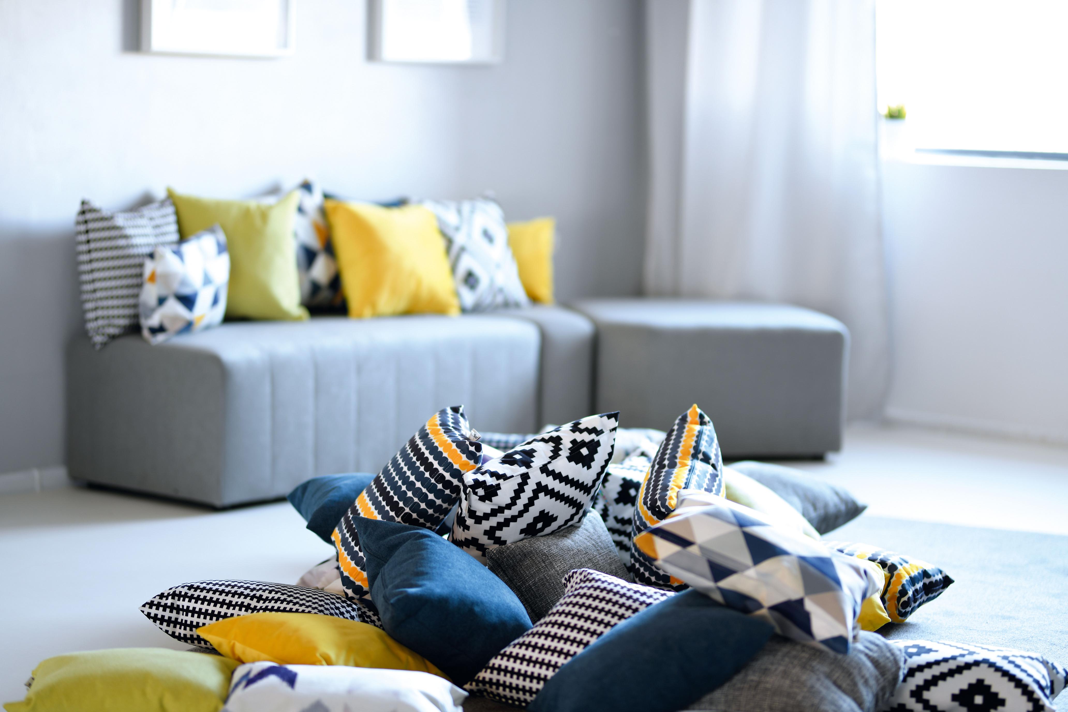 Bunte Kissen auf grauem Sofa im Gruppenraum.