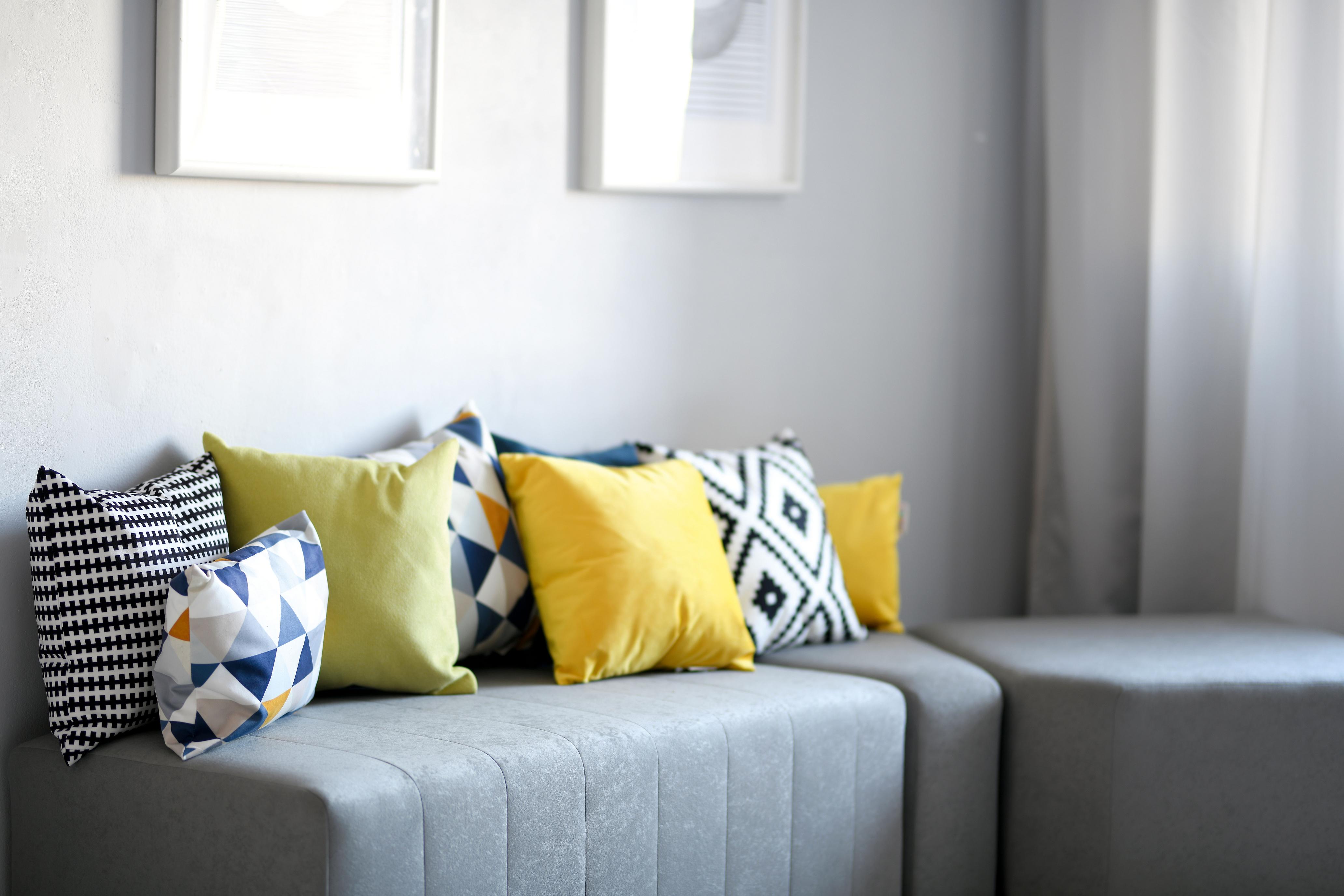 Bunte Kissen auf grauer Sitzlandschaft im Gruppenraum.