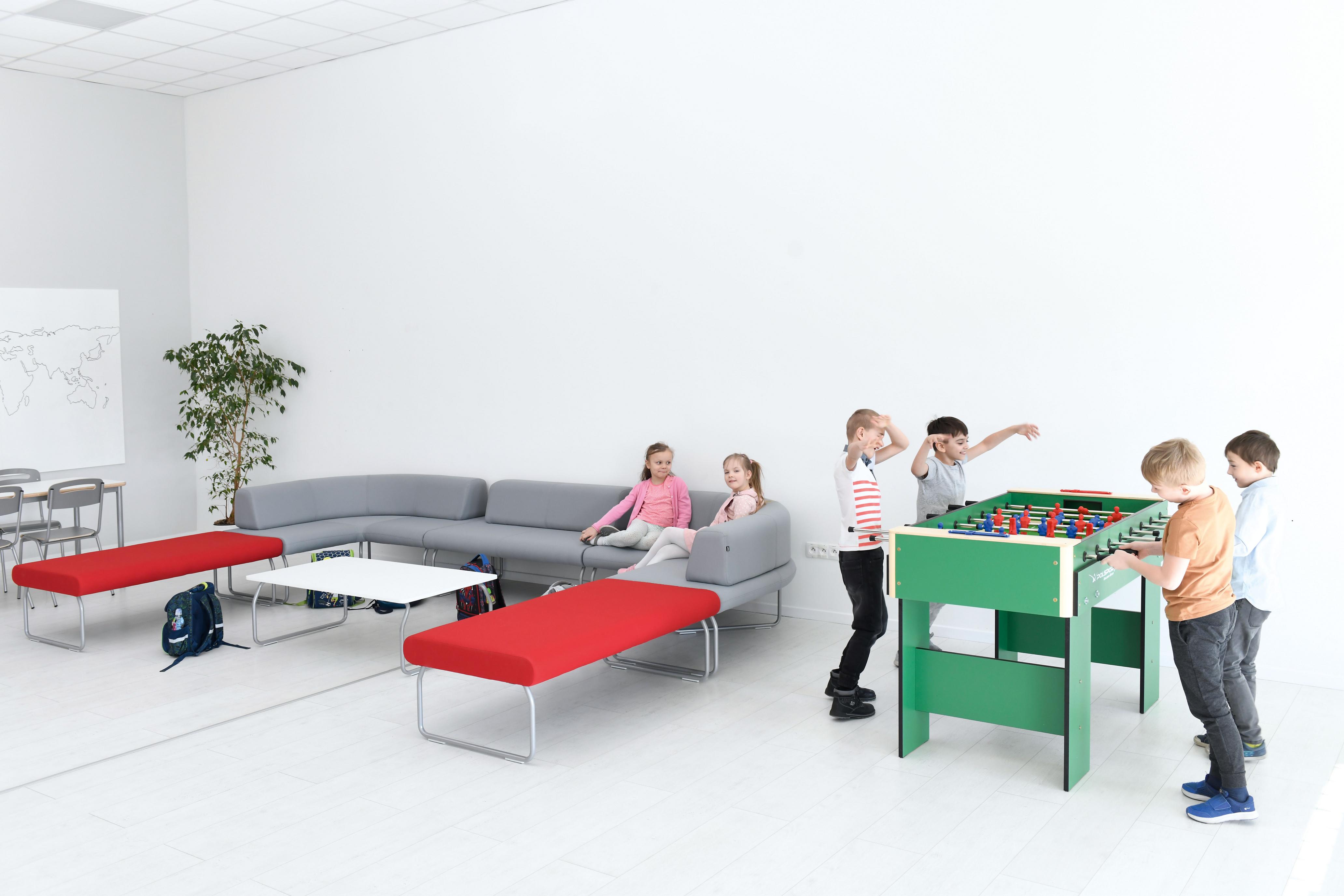 Kinder spielen in einem Raum mit Sitzlandschaft.