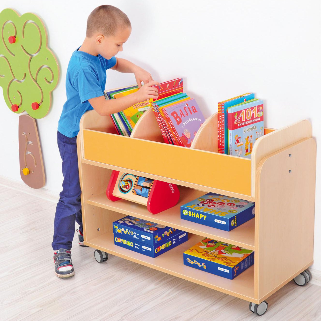 Kind sortiert Bücher im mobilen Bücherregal in der Leseecke. - Produkt wird im Kindergarten oder Schule genutzt.