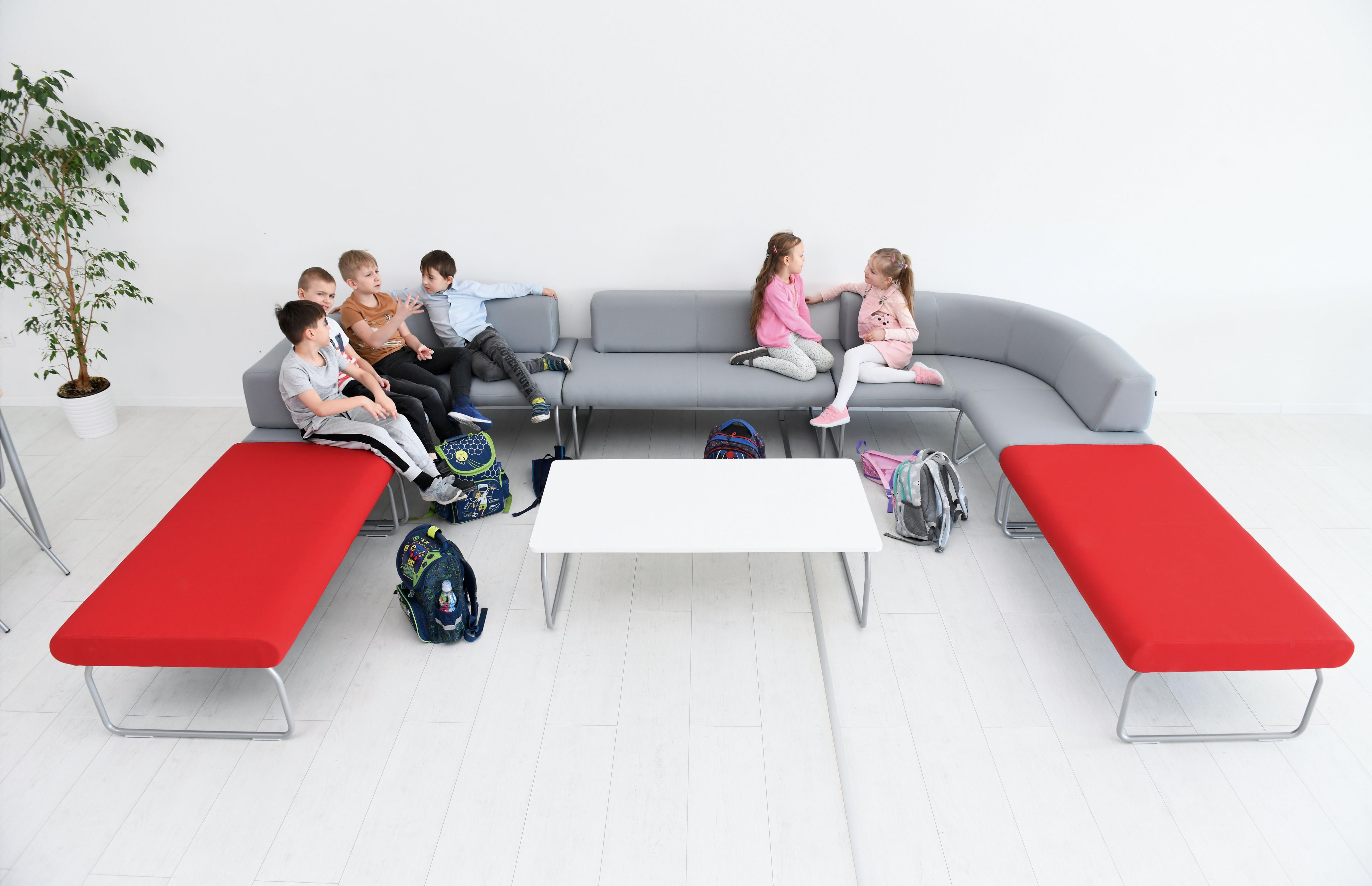 Kinder sitzen auf bunter Sitzlandschaft Flow im Raum.