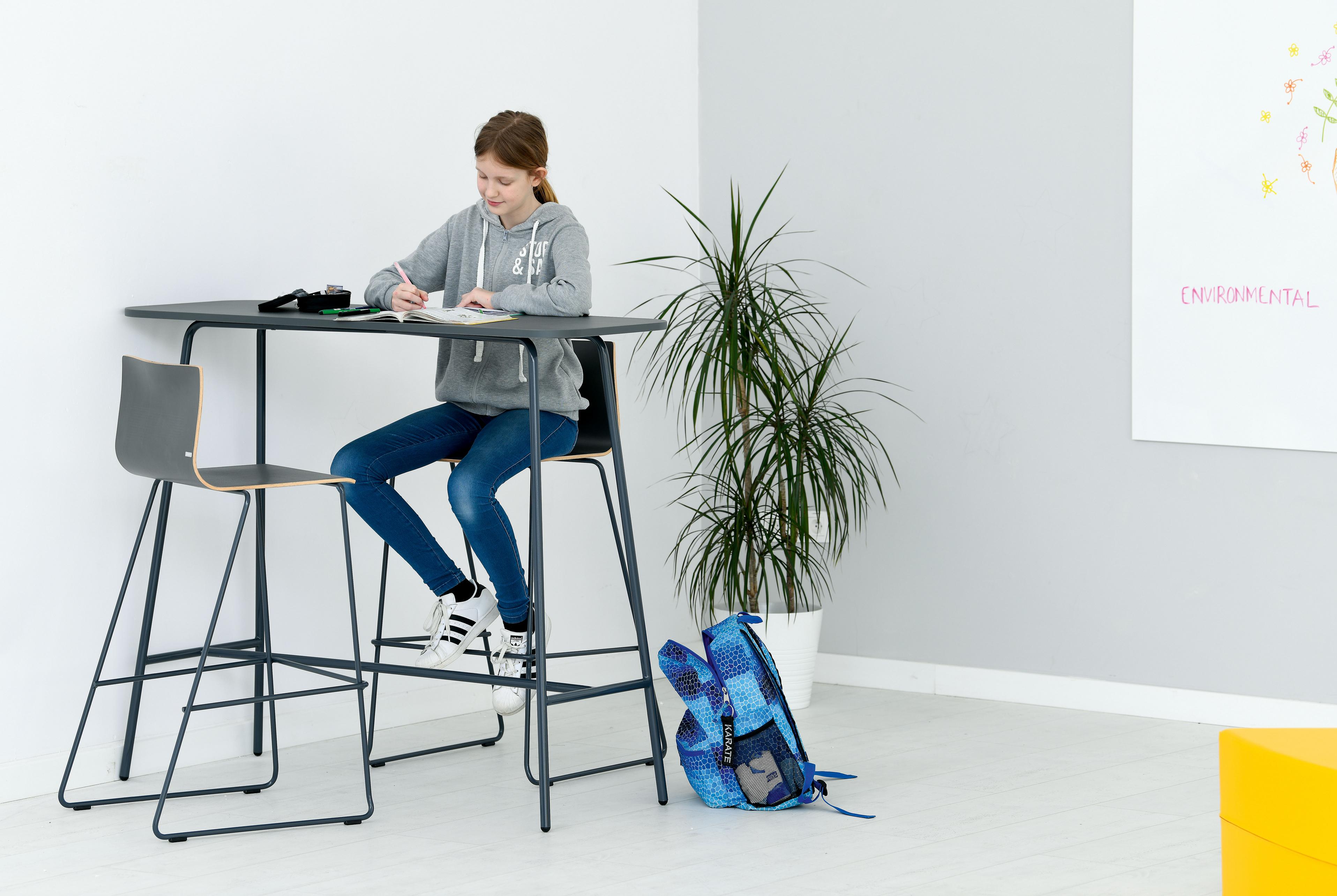 Junge Person am Hochtisch im modernen Lernraum.