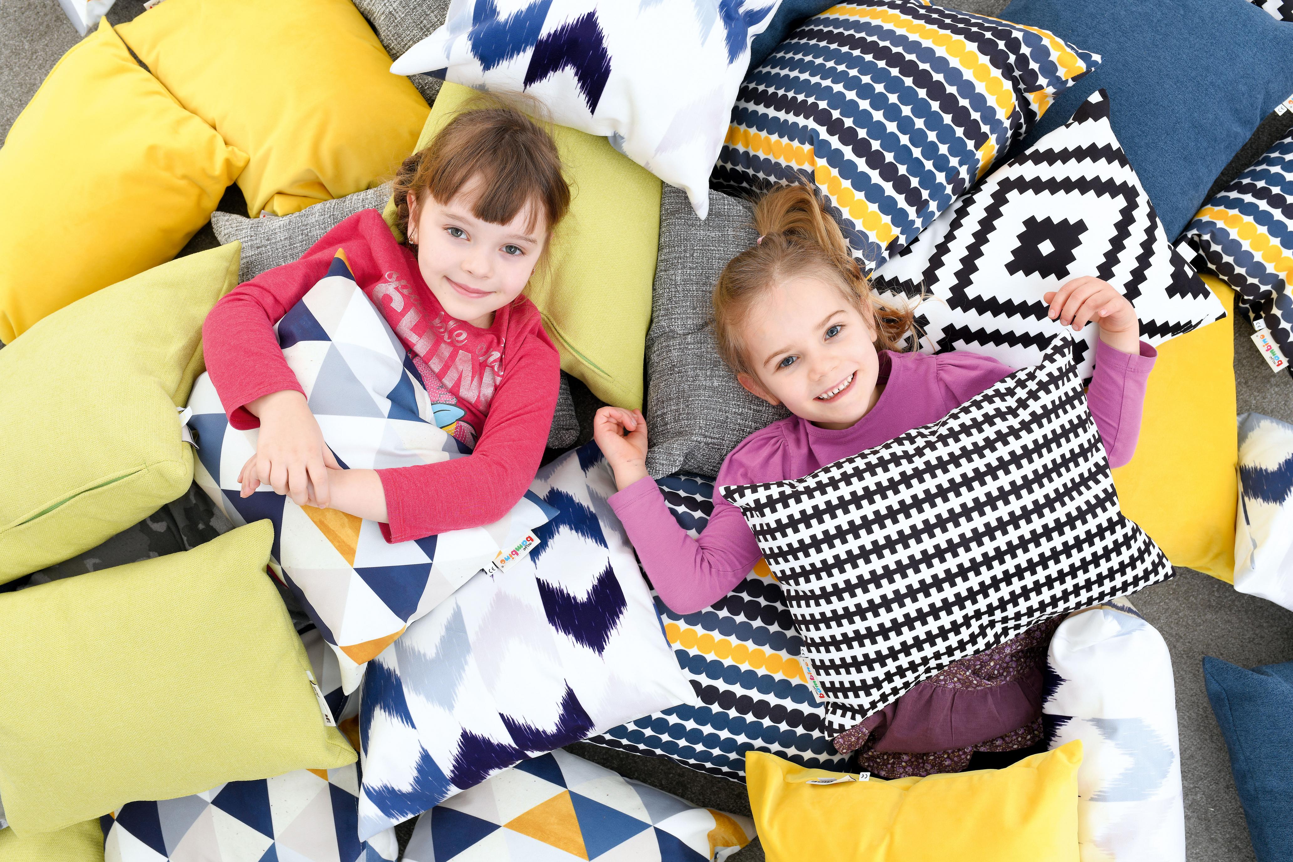 Kinder auf bunten Kissen im Gruppenraum liegend.