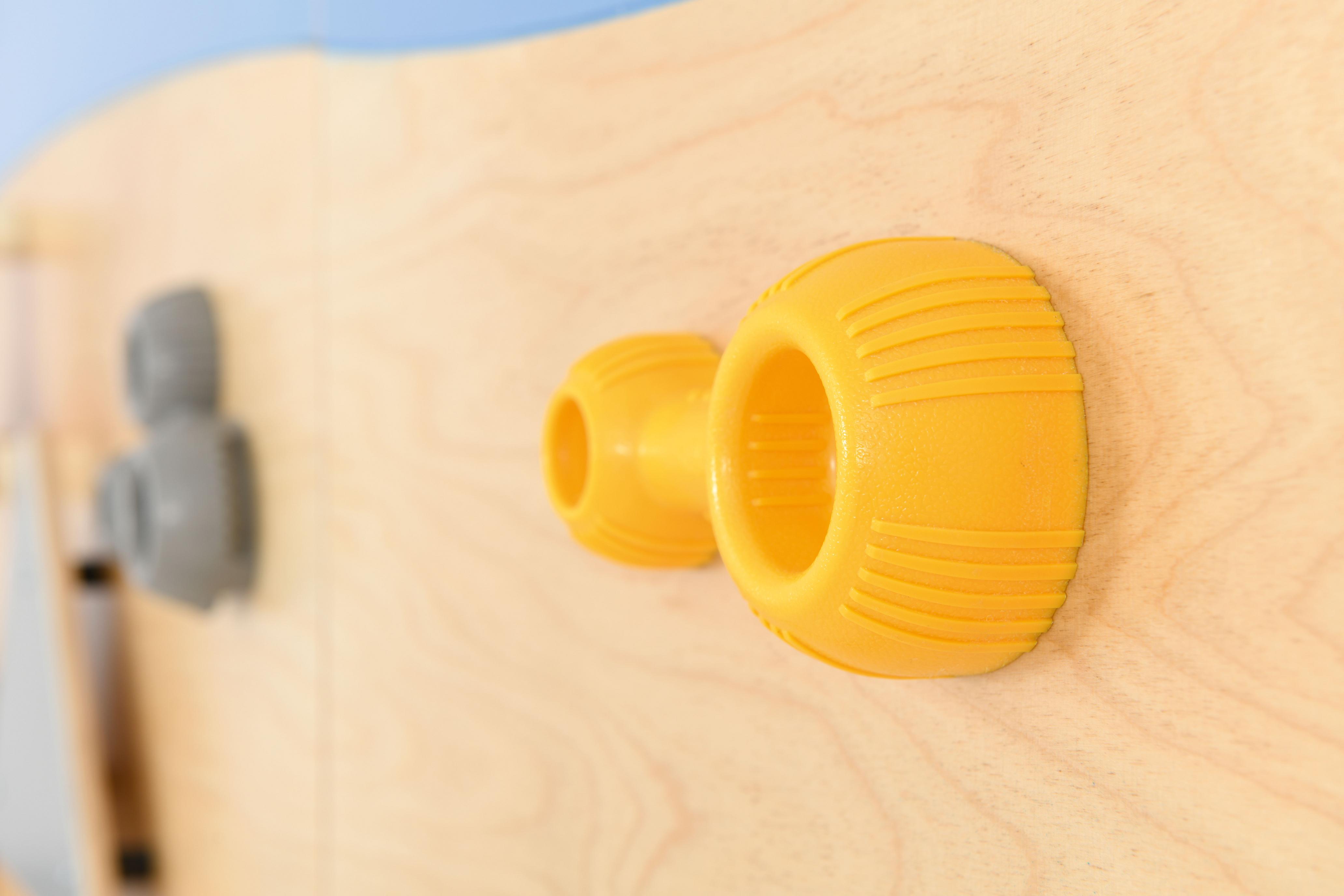 Bunte Klettergriffe an Holzbrett für Schulen und Kitas.