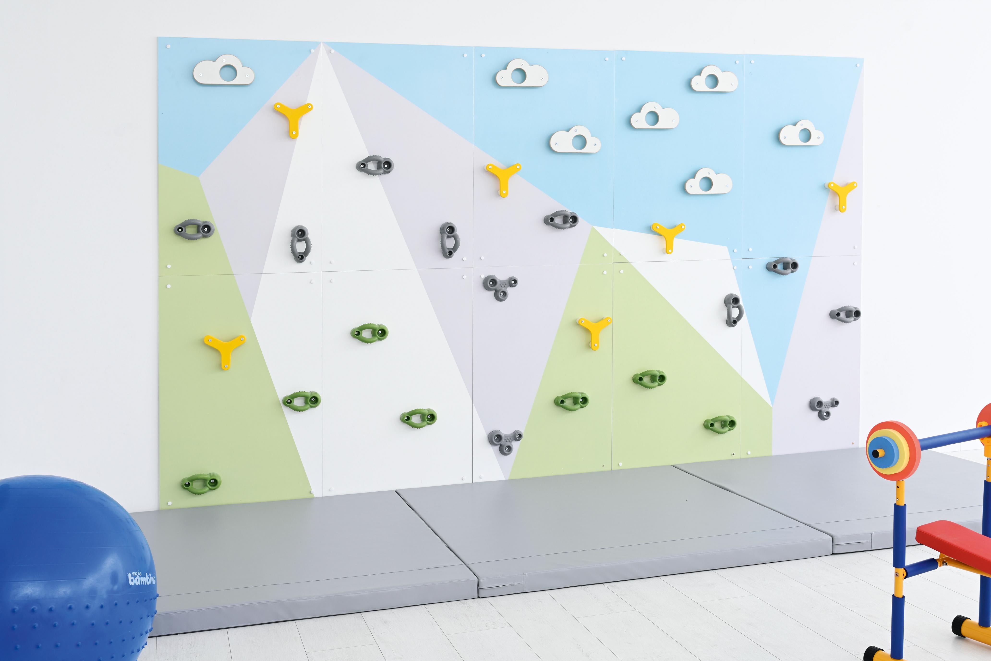 Bunte Kletterwand mit kindgerechtem Design in Sporthalle.