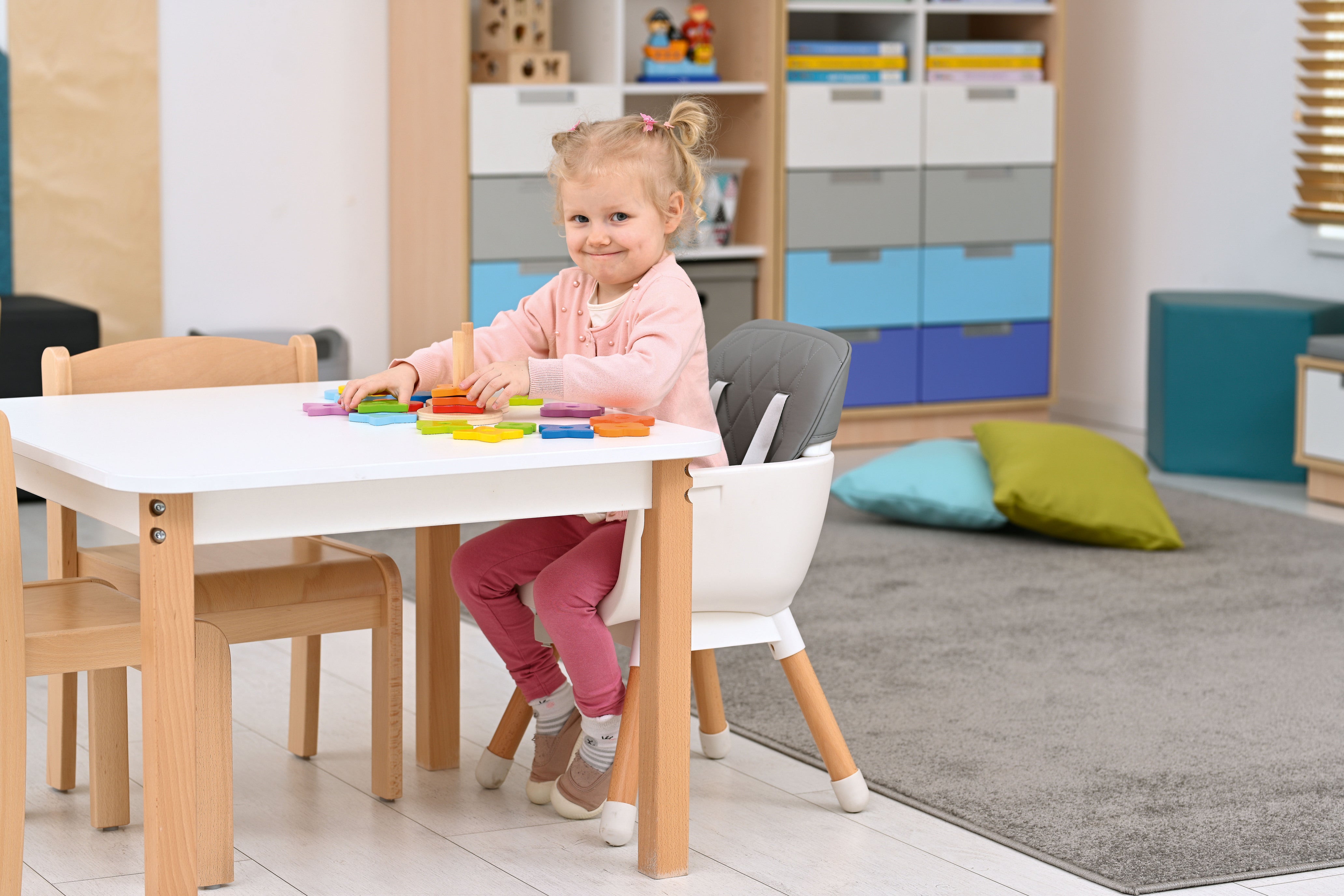 Hochstuhl für Krippe im Gruppenraum am Tisch mit Kind