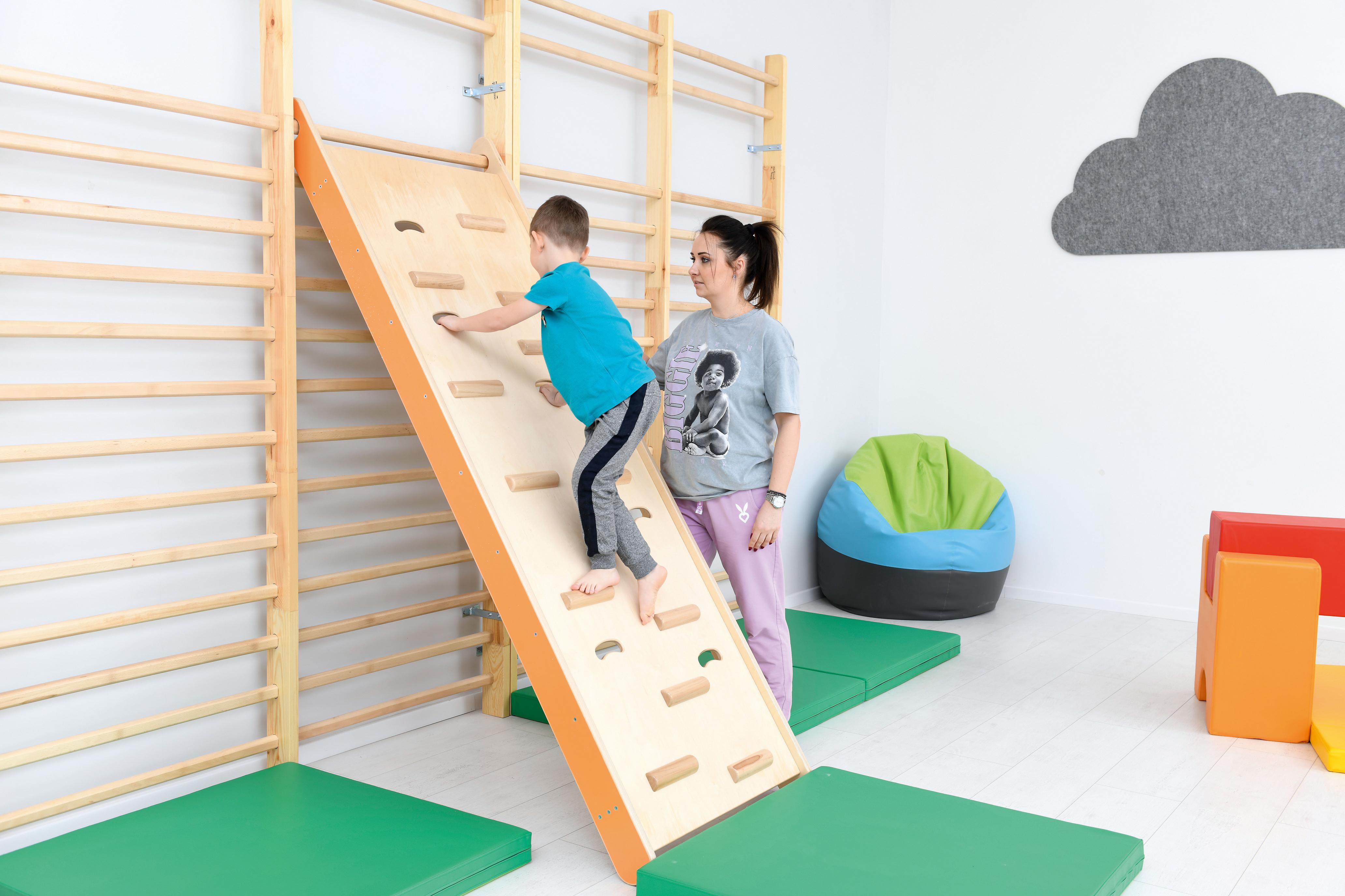 Kind klettert an Kletterwand in Kita-Sporthalle.