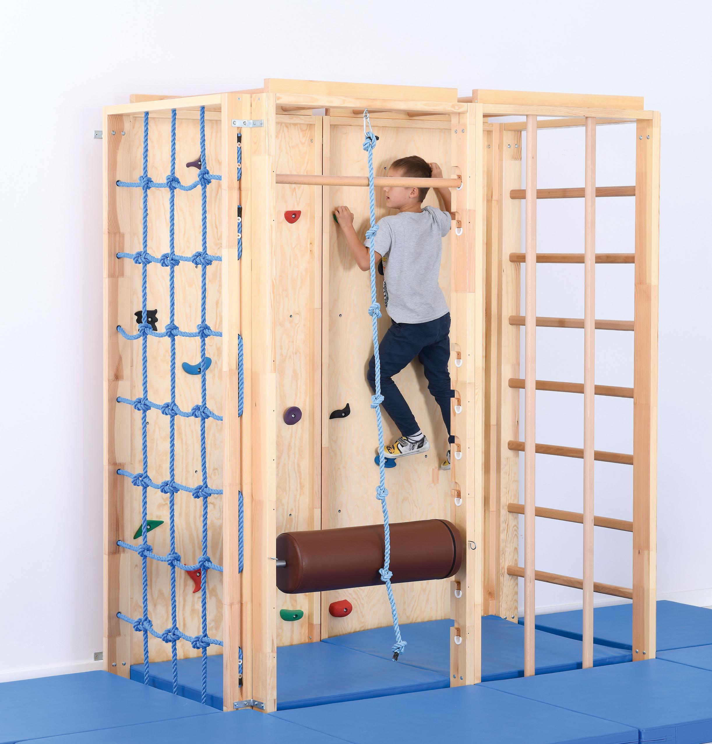 Kind klettert an Kletterwand in der Turnhalle.