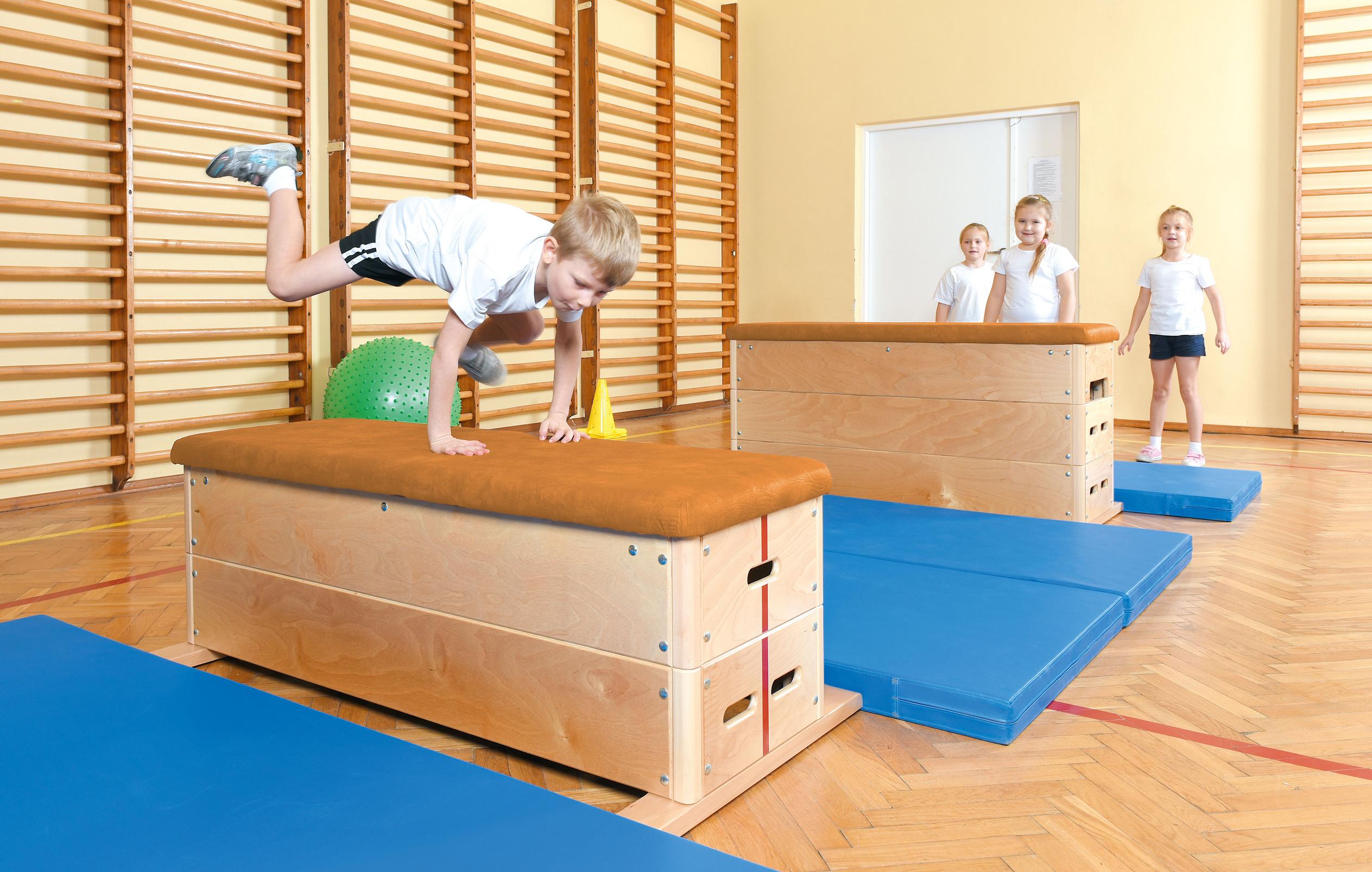 Kinder nutzen Sprungkasten für Turnhalle in der Sporthalle.