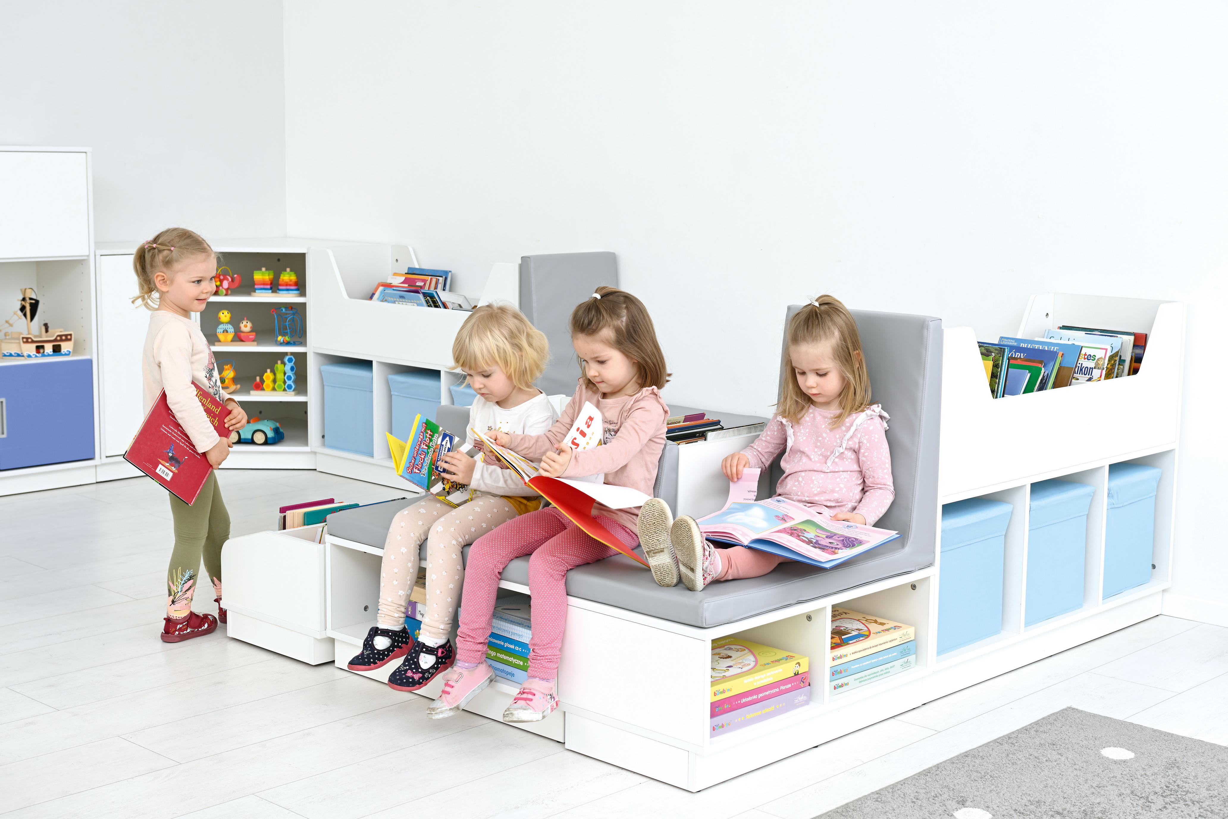 Kinder sitzen auf Bücherbank in gemütlicher Leseecke. - Produkt wird im Kindergarten oder Schule genutzt.