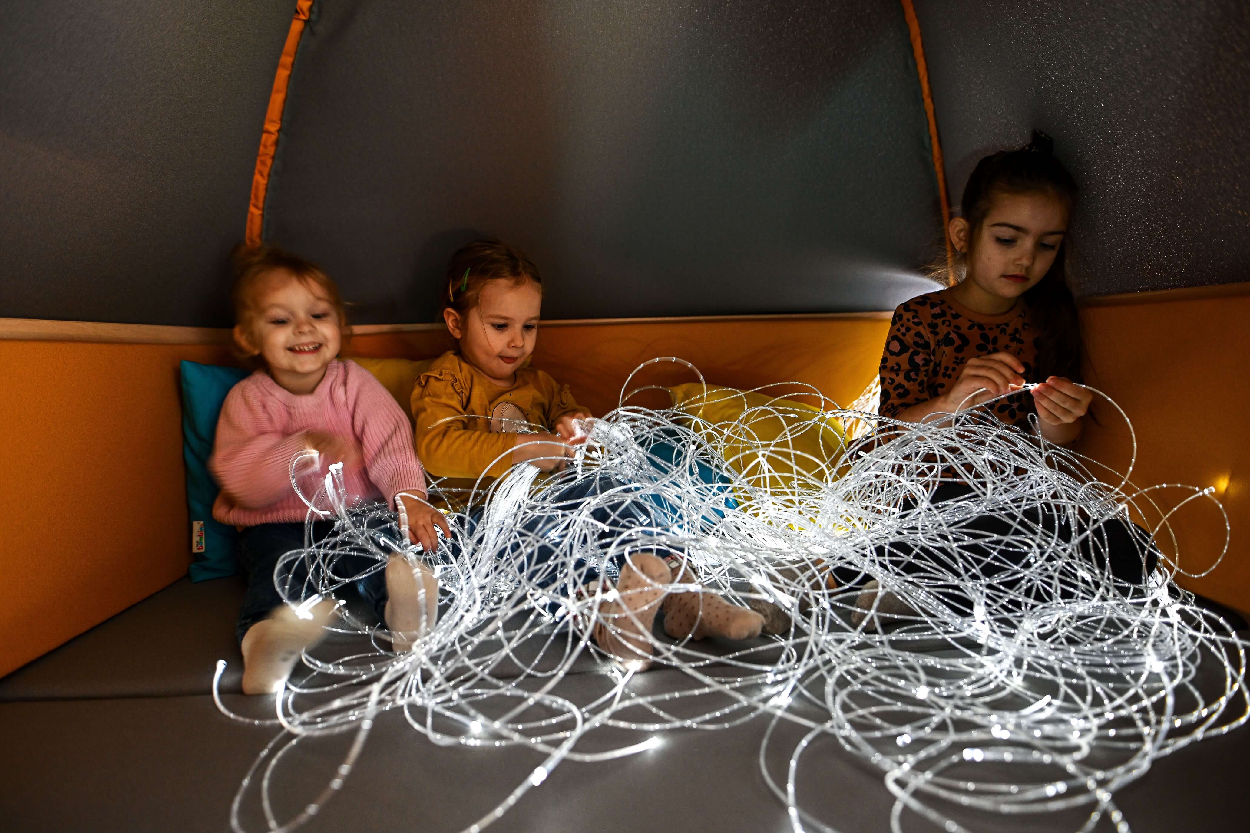 Sinneshöhle und Kuschelecke, gepolstert für Kindergarten und Krippen geschlossener Vorhang im Dunkeln mit Lichtern  und Kinder spielen