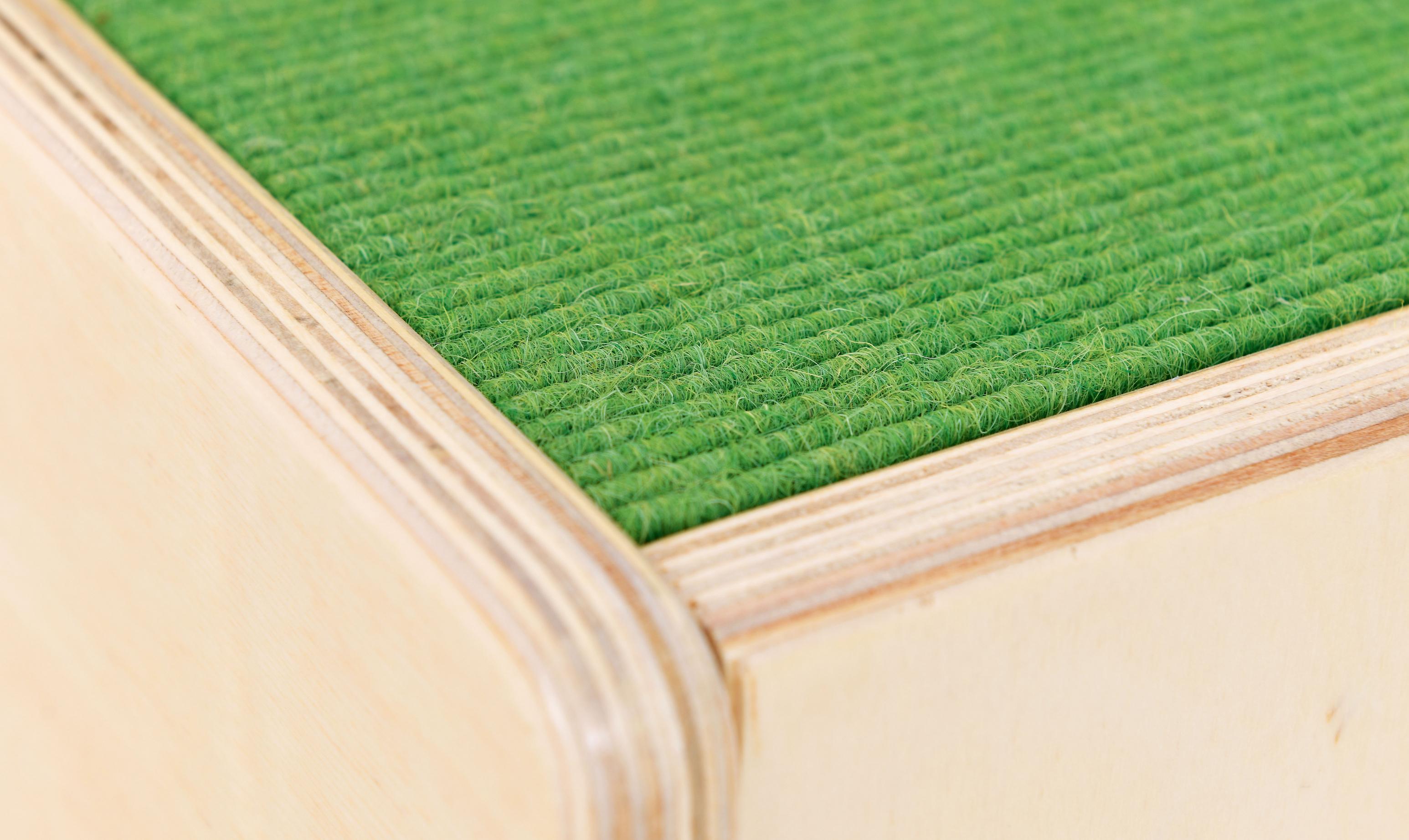 Grüner Teppich auf einer hölzernen Stufenpodest-Oberfläche.
