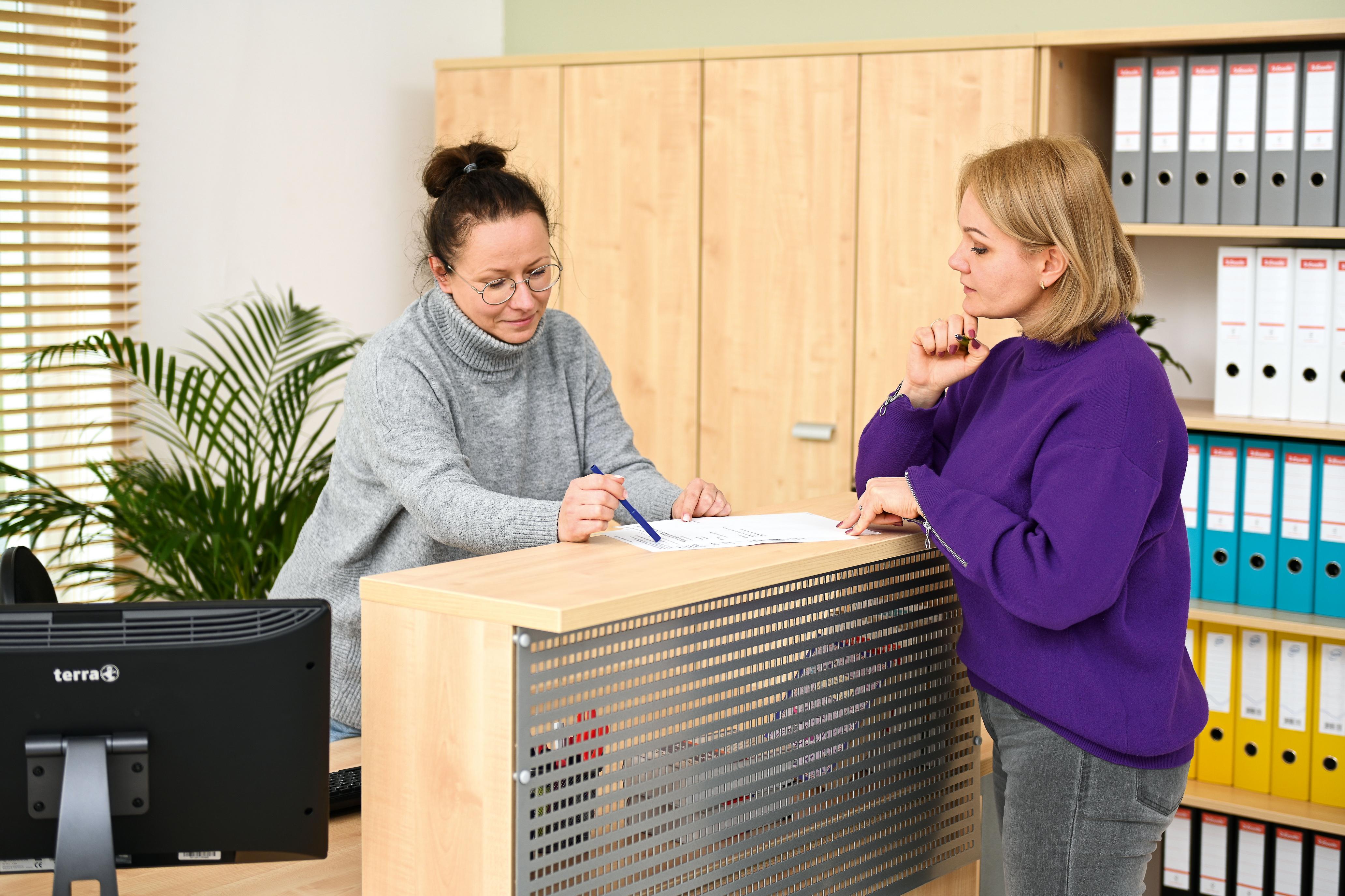 Zwei Personen arbeiten am OPTO Rezeptionstresen zusammen.