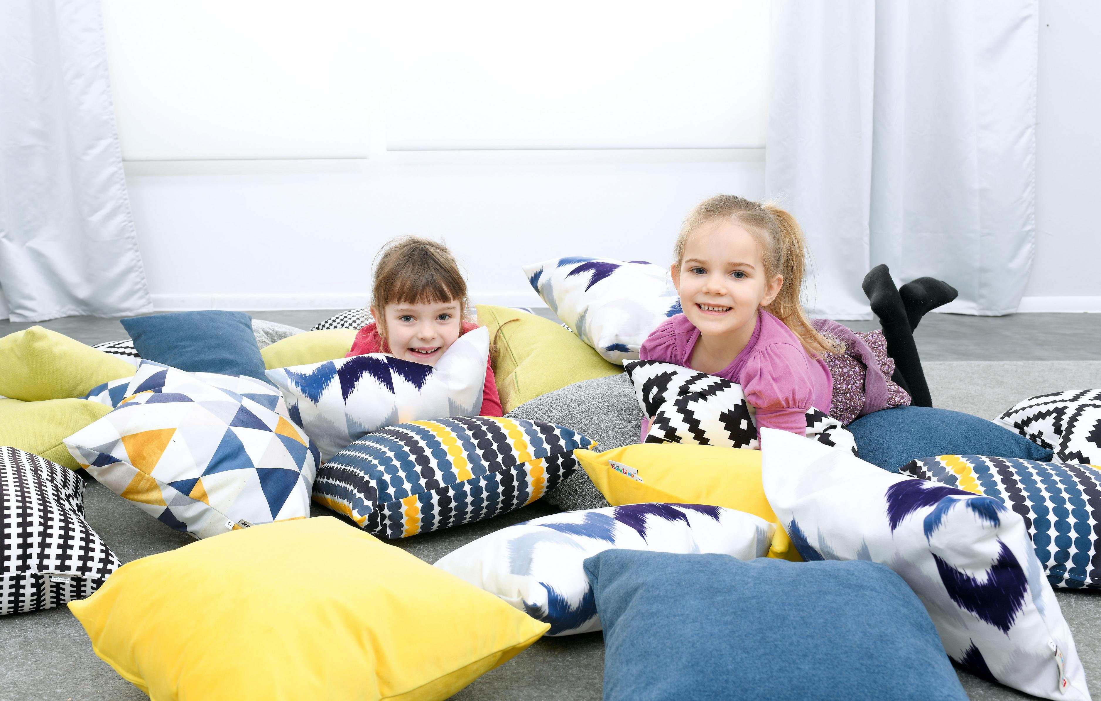 Kinder spielen fröhlich auf bunten Kissen.