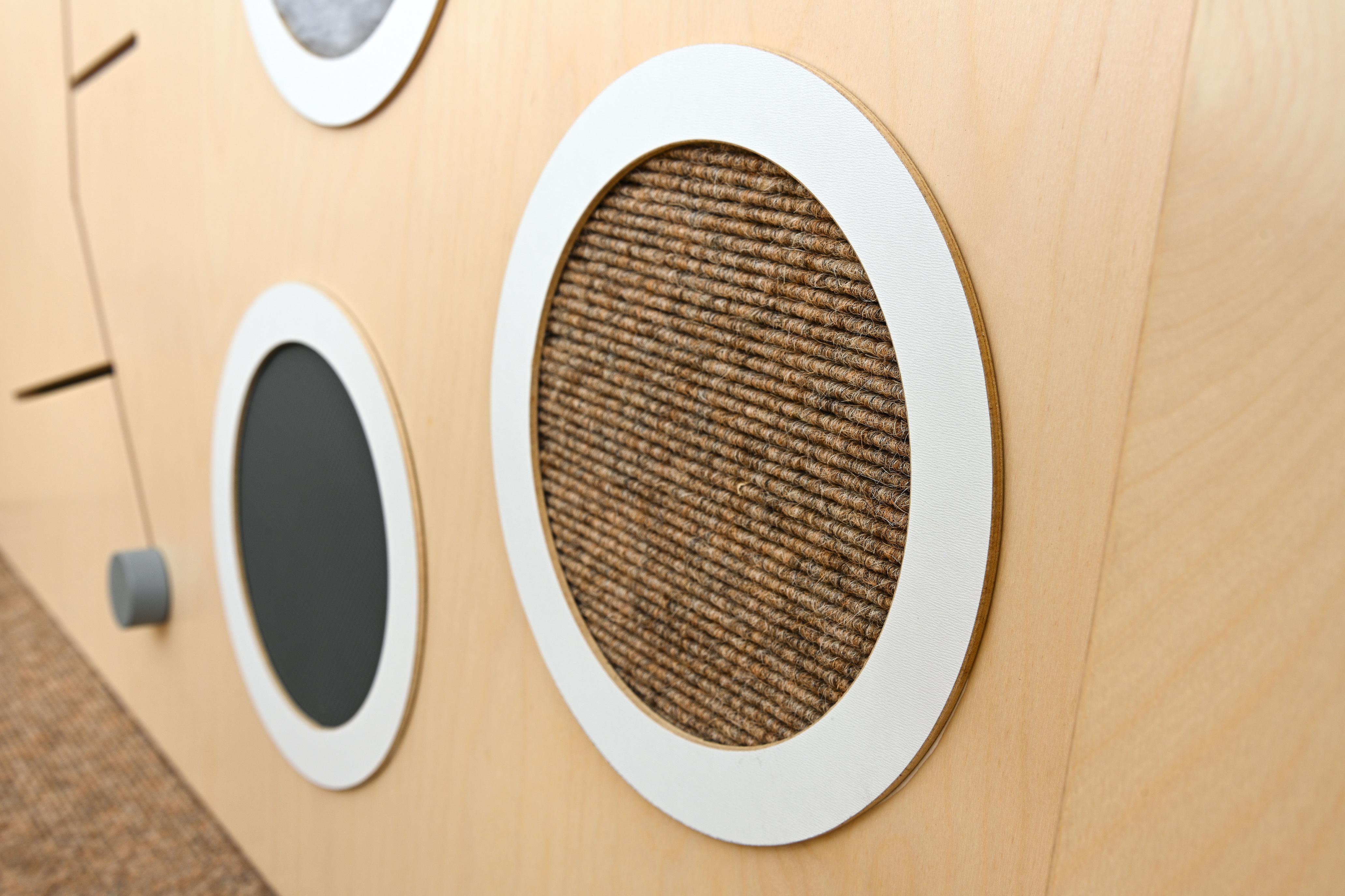 Sensorische Spielecke mit strukturierten Elementen auf Holzoberfläche.